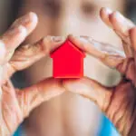 agent immobilier tenant une maison miniature