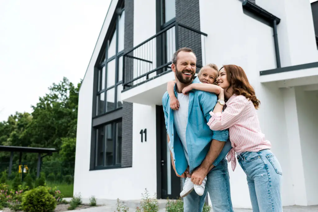 Famille heureuse devant une maison moderne